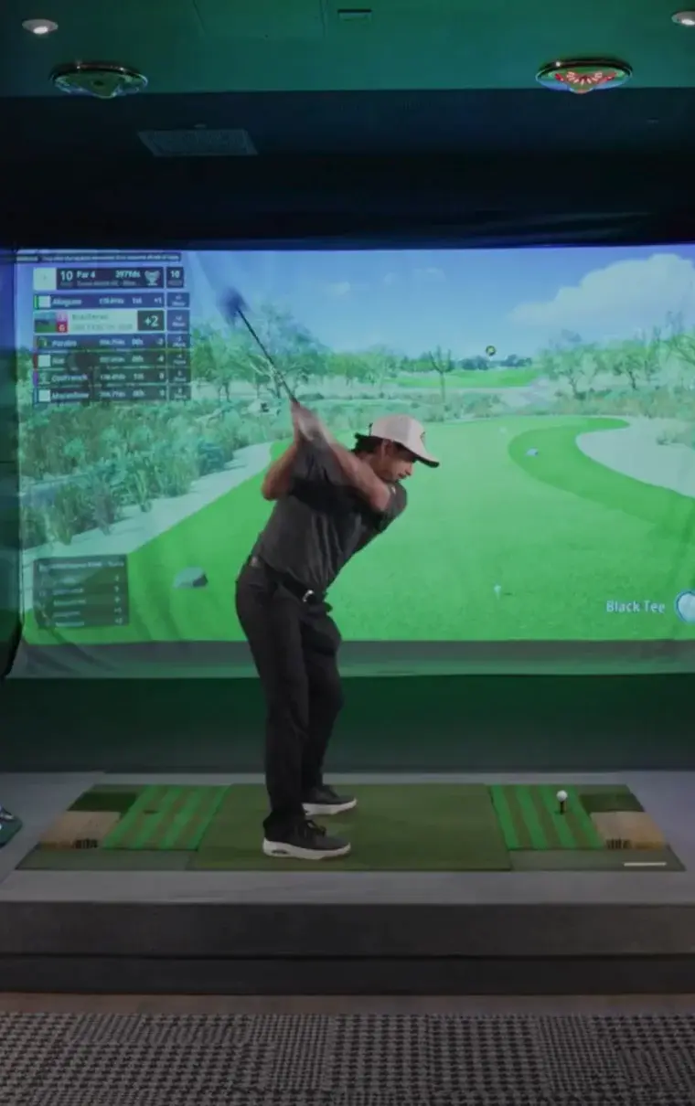 Golfer swinging in front of a simulator screen